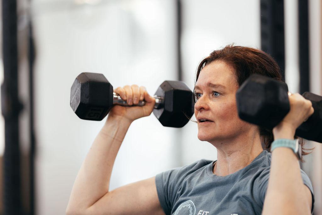 Member pressing dumbbells overhead